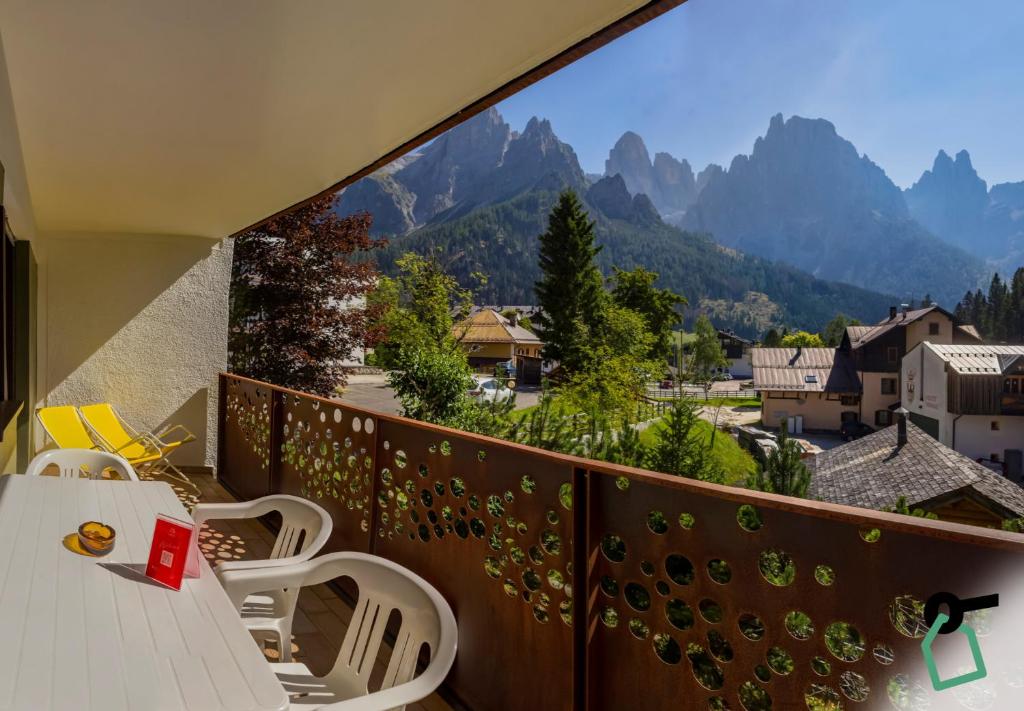 a balcony with a table and chairs and mountains at HOTIDAY Residence San Martino in San Martino di Castrozza