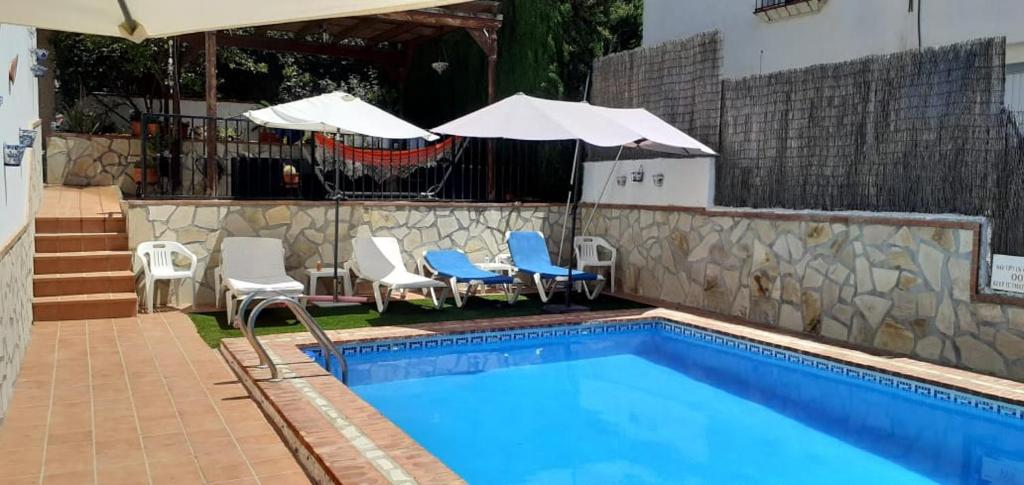 a swimming pool with chairs and umbrellas next to a building at Casa Magnolia in Dúrcal