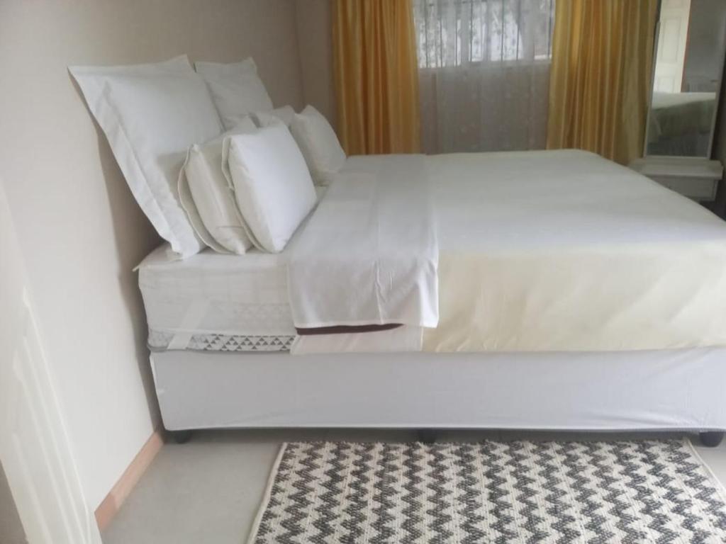 1 cama blanca grande con almohadas blancas y alfombra en Cottage on 14th, en East London