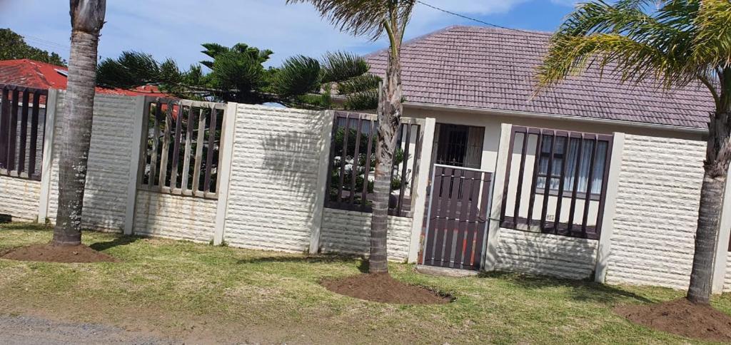 a white fence in front of a house with palm trees at Cottage on 14th in East London