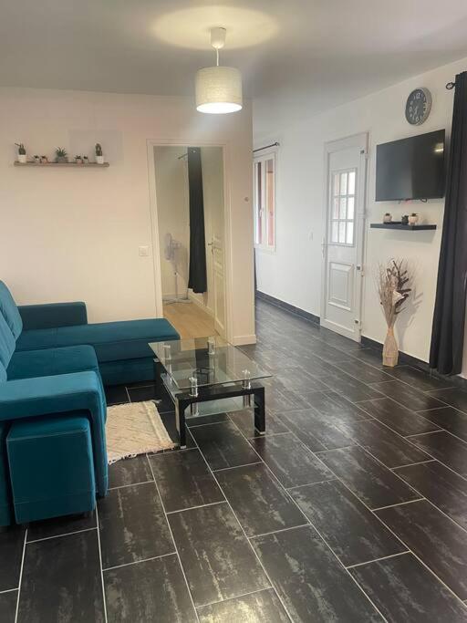 un salon avec un canapé bleu et une table dans l'établissement L7 -Villiers-le-Bel proche Aéroport ROISSY CHARLES DE GAULLES & PARIS, à Villiers-le-Bel