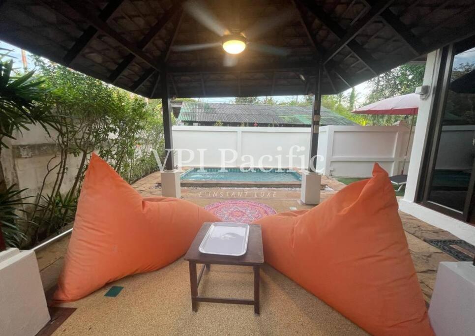 an orange couch on a patio with a table at Jacuzzi Pool Villa Isabelle 1bed in Nathon Bay
