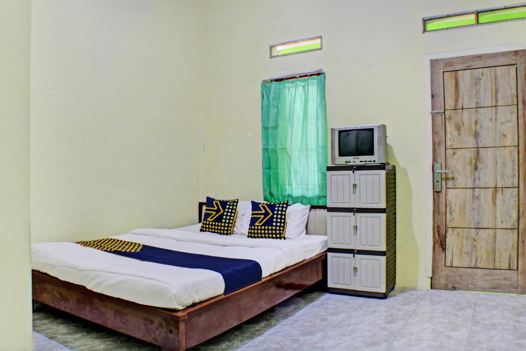 1 dormitorio con 1 cama y TV. en SPOT ON 93089 Homestay Kamar Hijau Syariah, en Bandar Lampung