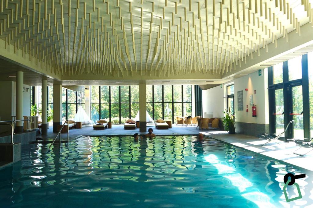 a hotel lobby with a swimming pool with a large ceiling at HOTIDAY Residence Campiglio in Madonna di Campiglio