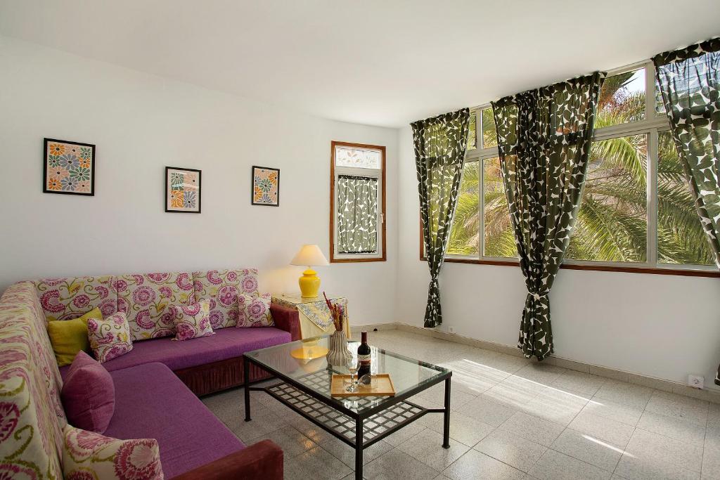 ein Wohnzimmer mit einem lila Sofa und einem Tisch in der Unterkunft Apartamento Danoe 1 in Mogán