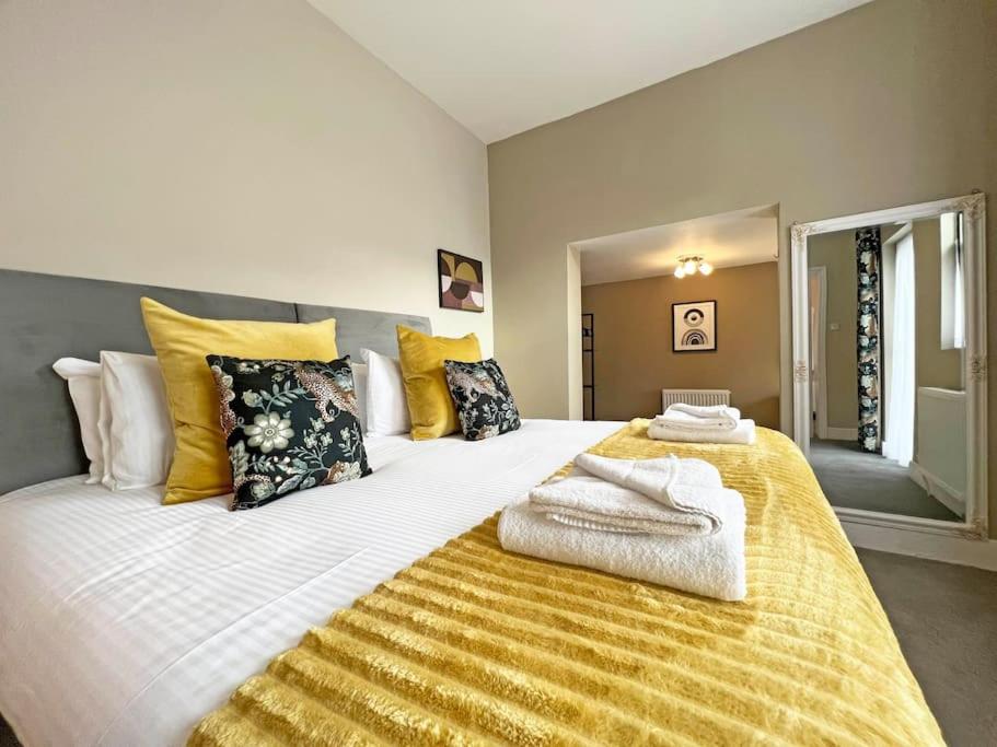 uma cama grande com lençóis e almofadas amarelos e brancos em 2-Bed Victorian Elegance em Chester