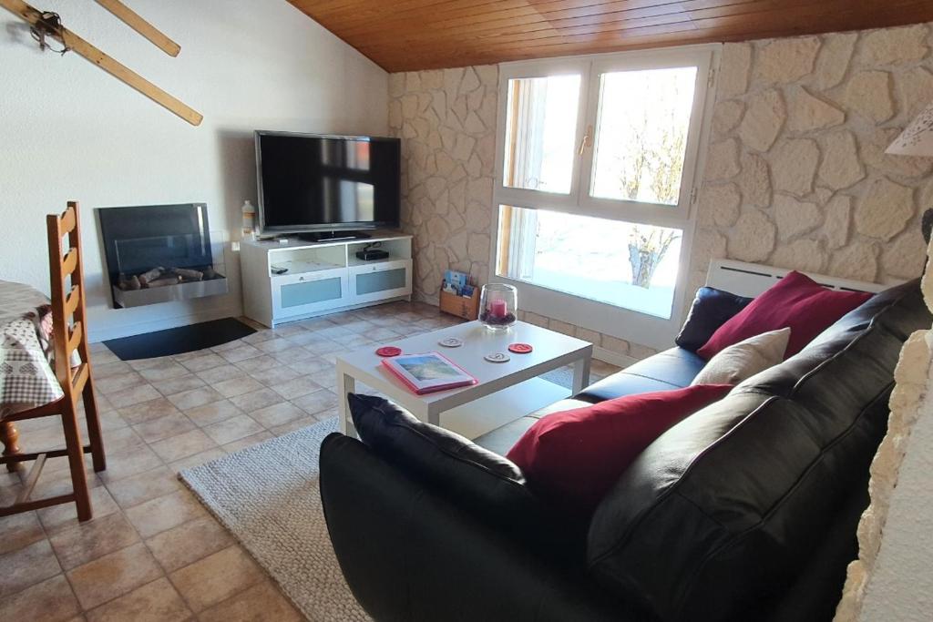 a living room with a couch and a tv at Le Logis de Pimpi in Lamoura