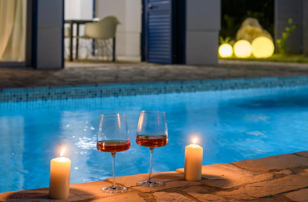 two glasses of wine and candles next to a swimming pool at Holiday home Blue Sky in Zaostrog