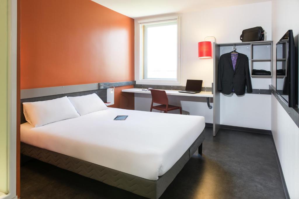 a hotel room with a bed and a desk at ibis budget Aéroport Lyon Saint Exupéry in Saint-Exupéry