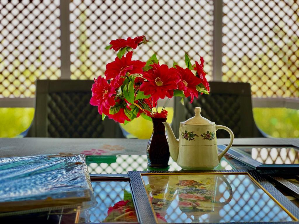 un jarrón con flores rojas sentado en una mesa en Everest Guest House, en Gulmarg