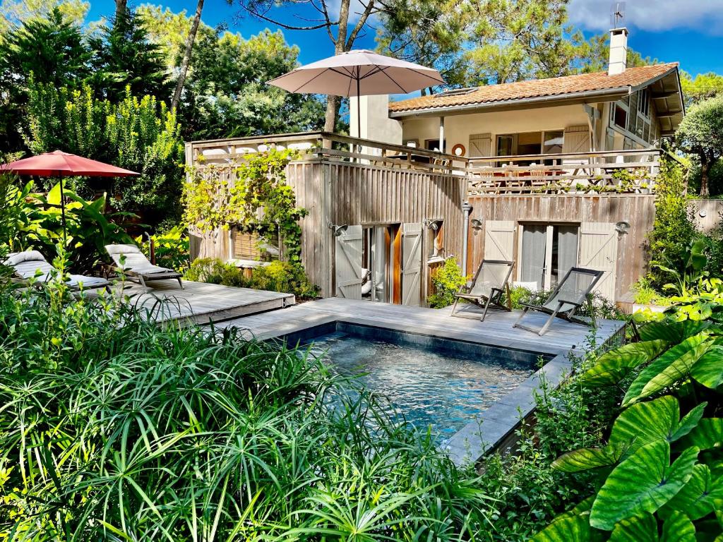 une maison dotée d'une piscine avec des chaises et un parasol dans l'établissement Villa d’exception avec piscine à la pointe, à Lège-Cap-Ferret
