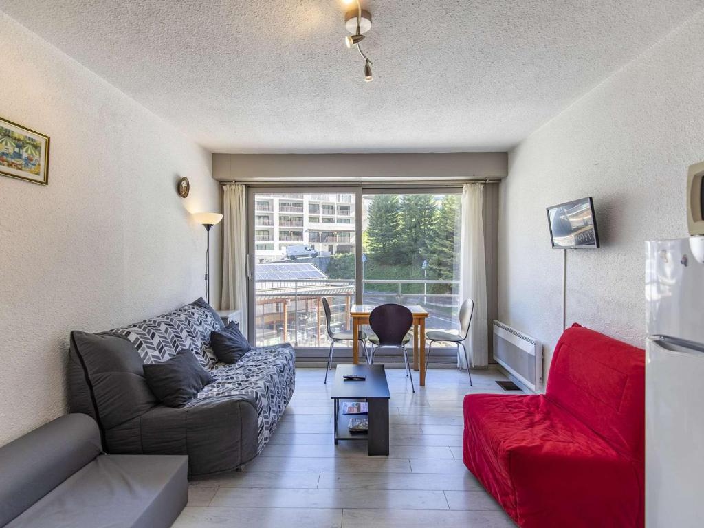 ein Wohnzimmer mit einem Sofa und einem roten Stuhl in der Unterkunft Studio Gourette, 1 pièce, 3 personnes - FR-1-400-12 in Gourette