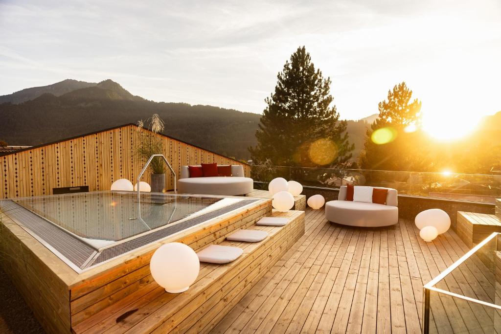 a hot tub on a wooden deck with chairs and tables at Hotel Franks in Oberstdorf