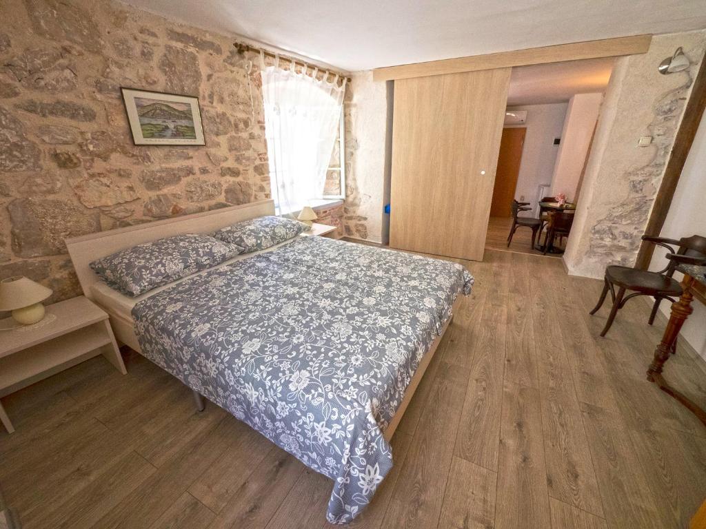 a bedroom with a bed and a stone wall at Guesthouse Merla in Šibenik