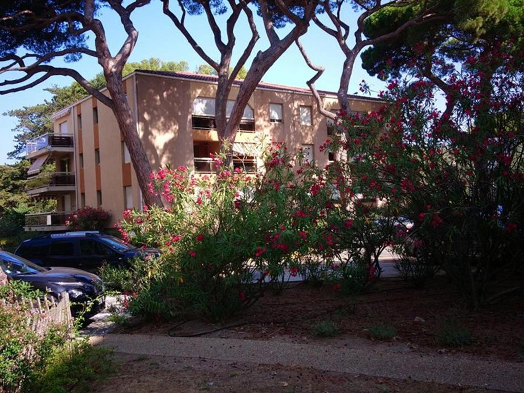 un bâtiment avec beaucoup de fleurs devant lui dans l'établissement Appartement T2 Cabine avec Grande Terrasse, Proche Port, Plages et Commerces, Parking Inclus - FR-1-335-178, à Hyères
