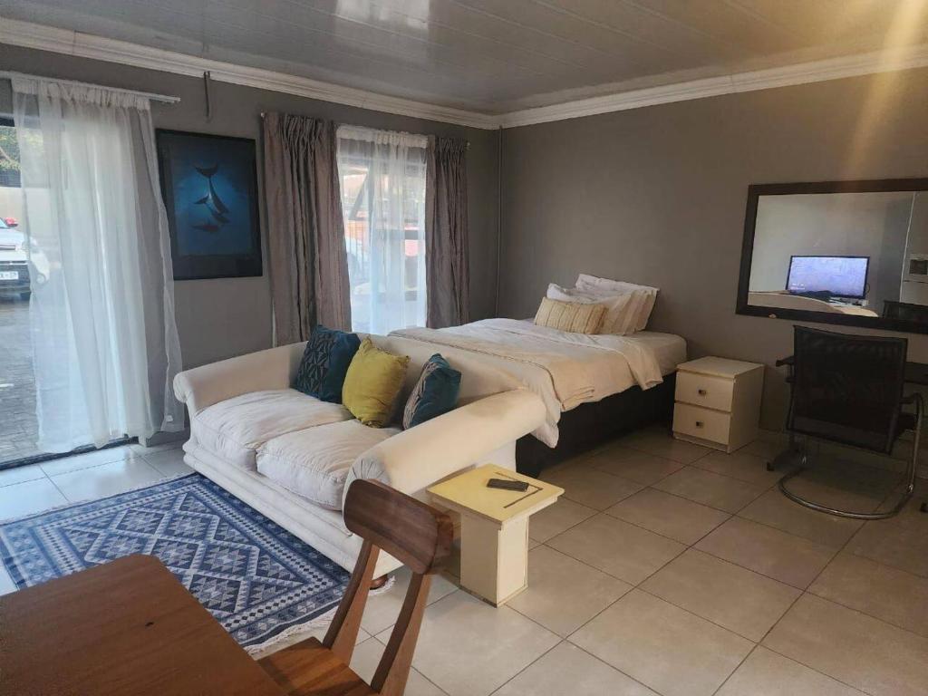 - un salon avec un canapé et un lit dans l'établissement Tenlet guesthouse, à Pretoria