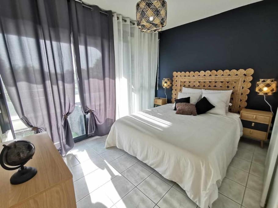 une chambre avec un grand lit et un mur bleu dans l'établissement Le Mazette YourHostHelper, à Narbonne