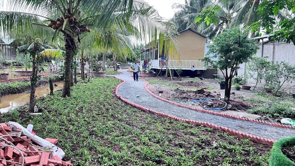 eine Person, die vor einem Haus einen Pfad entlang geht in der Unterkunft Homestay Cô Hai Garden in Ấp Vĩnh Hưng