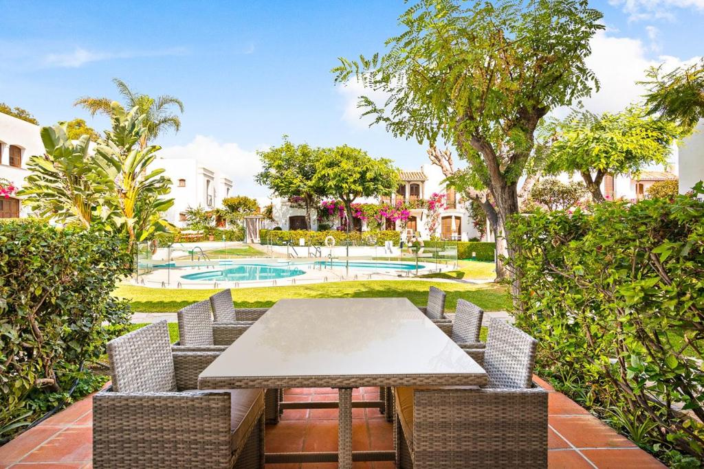 una zona pranzo all'aperto con tavolo, sedie e piscina di Villacana 2907 a Estepona