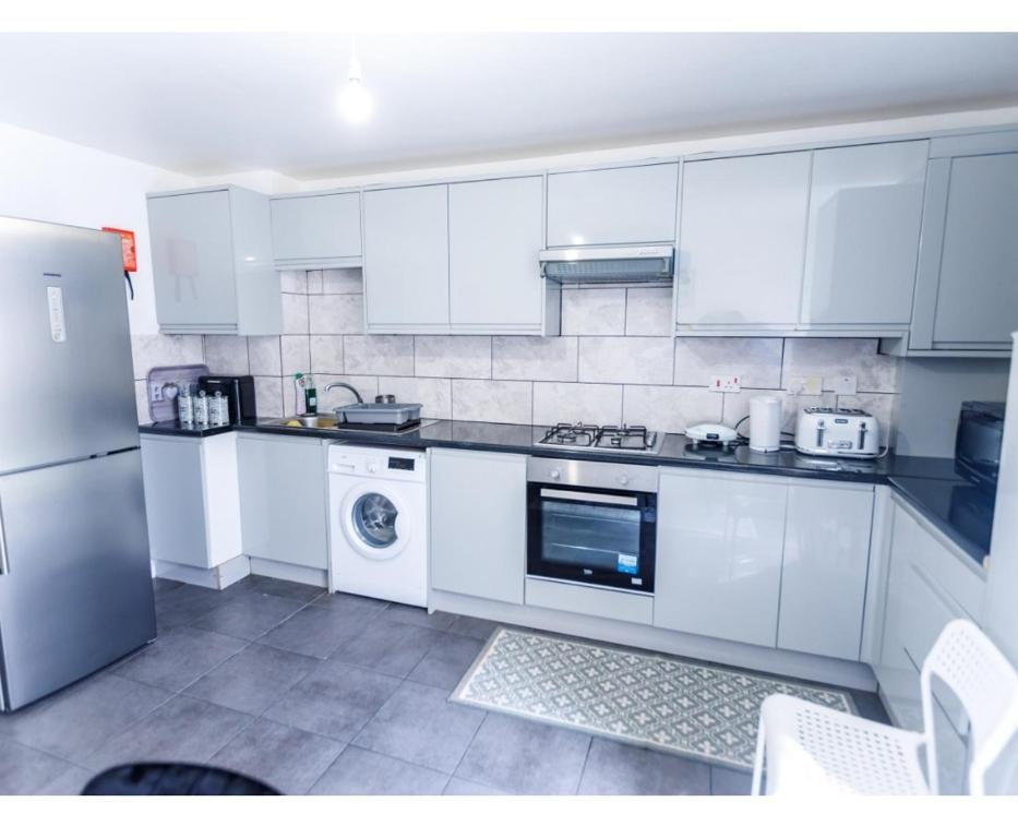 cocina con armarios blancos, lavadora y secadora en 3 bedrooms House with nice park view en Thamesmead