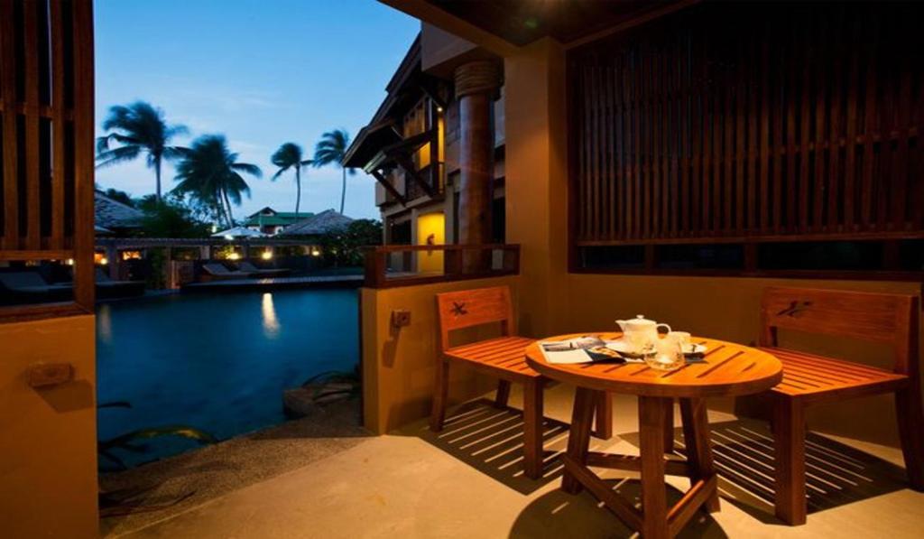 a table and chairs on a patio with a view of the water at Deva Beach Resort Samui in Choeng Mon Beach