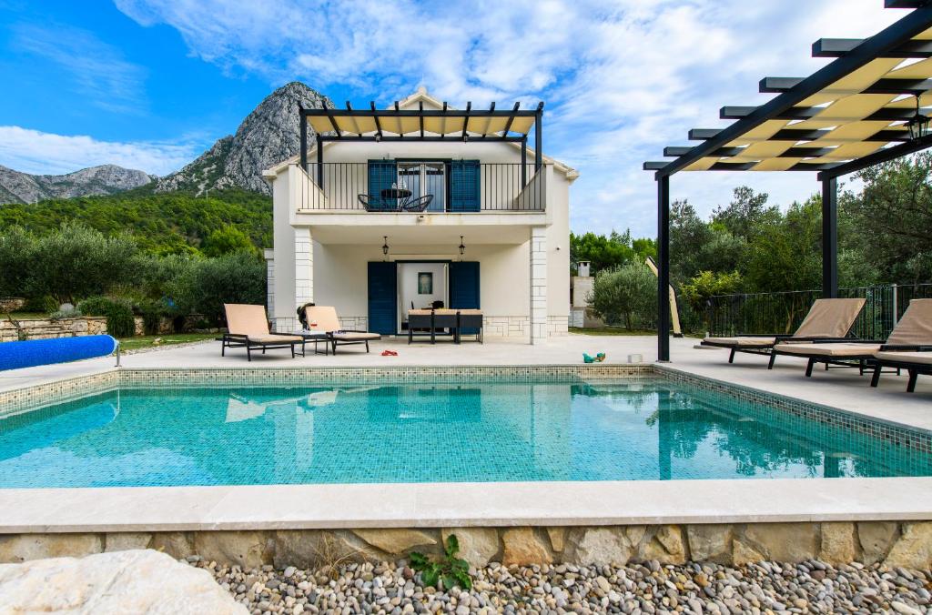 a villa with a swimming pool and a house at Holiday home Blue Stone in Zaostrog