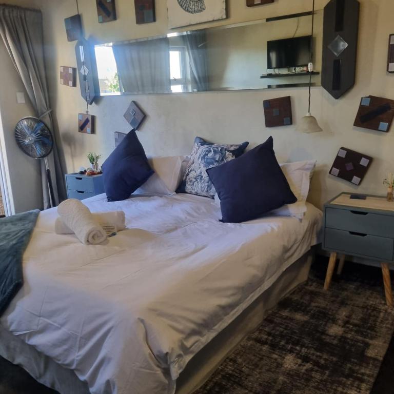 a large white bed with blue pillows in a room at Bedrock- Executive Self Catering Room in Cape Town