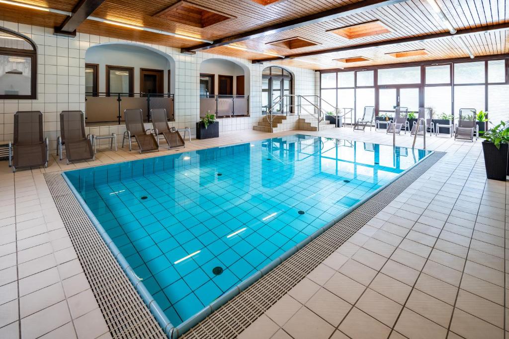 a large indoor pool with blue water in a building at Hotel Zur Post in Pirna