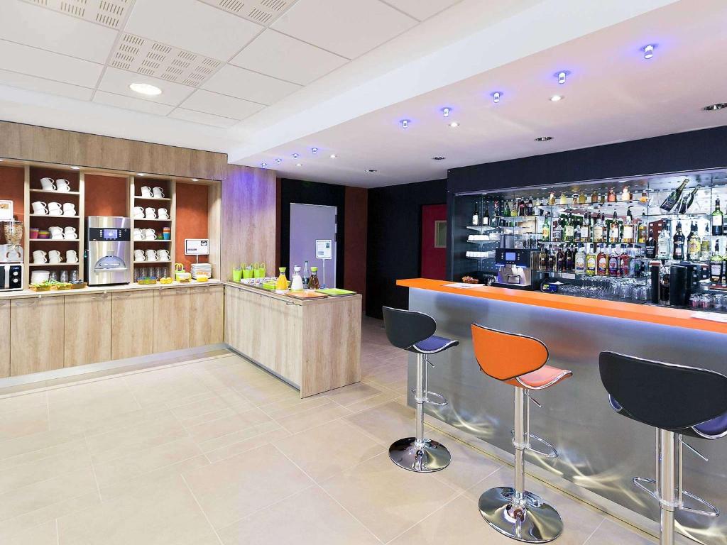 a bar with orange and blue chairs in a room at ibis Styles Flers in Flers