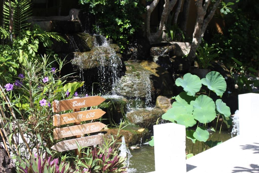 a fountain in a garden with a waterfall at Deva Beach Resort Samui in Choeng Mon Beach