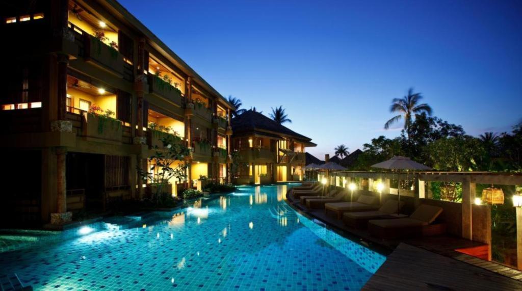 a swimming pool in front of a building at night at Deva Beach Resort Samui in Choeng Mon Beach