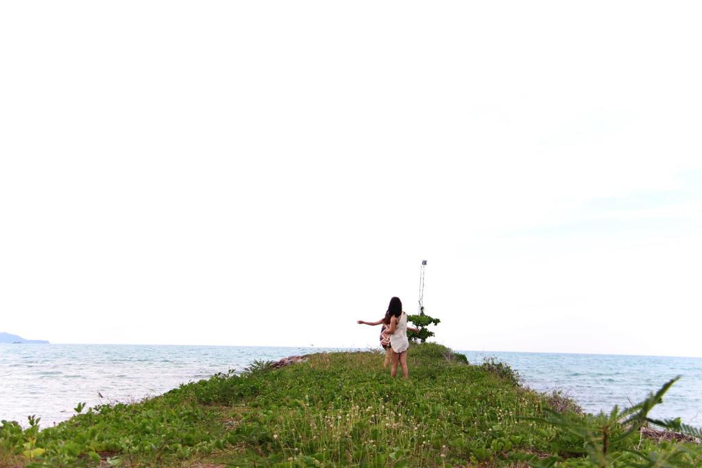a woman standing on a hill by the ocean at Deva Beach Resort Samui in Choeng Mon Beach