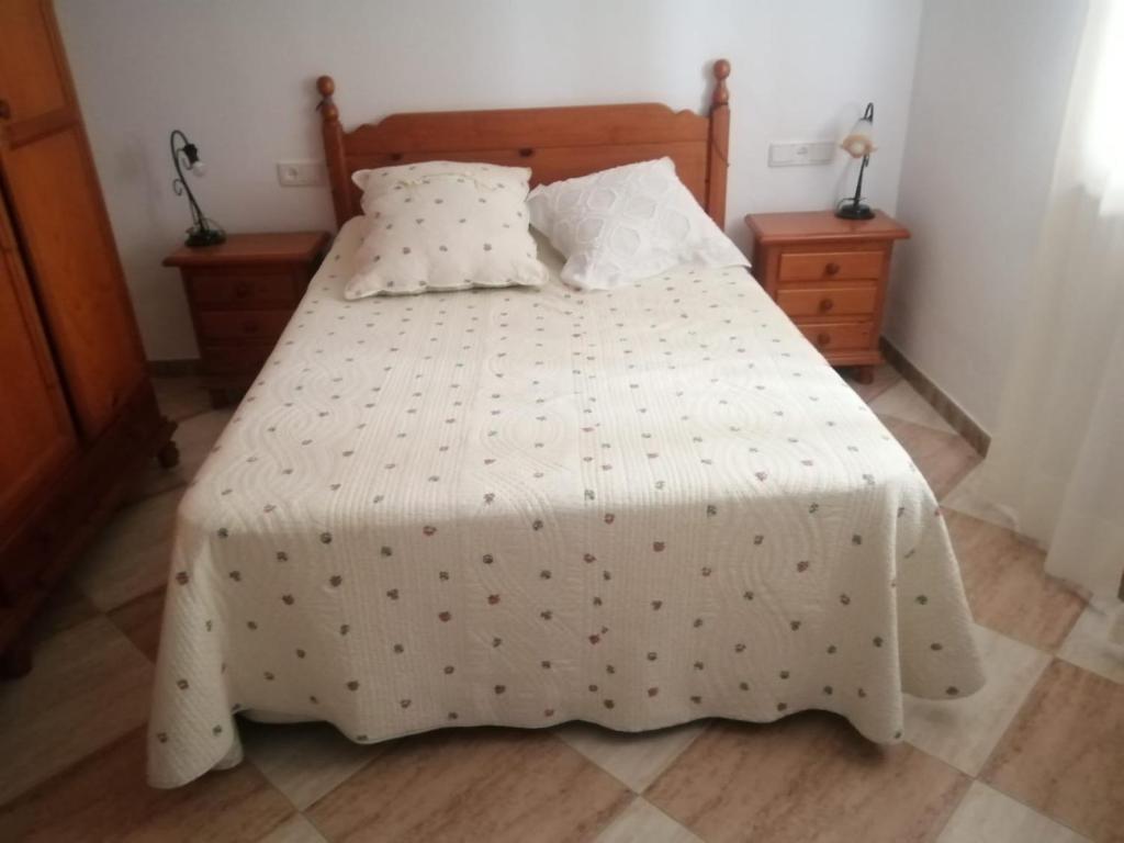 1 dormitorio con 1 cama con edredón blanco en El Rincón del Marqués en Alcalá de los Gazules