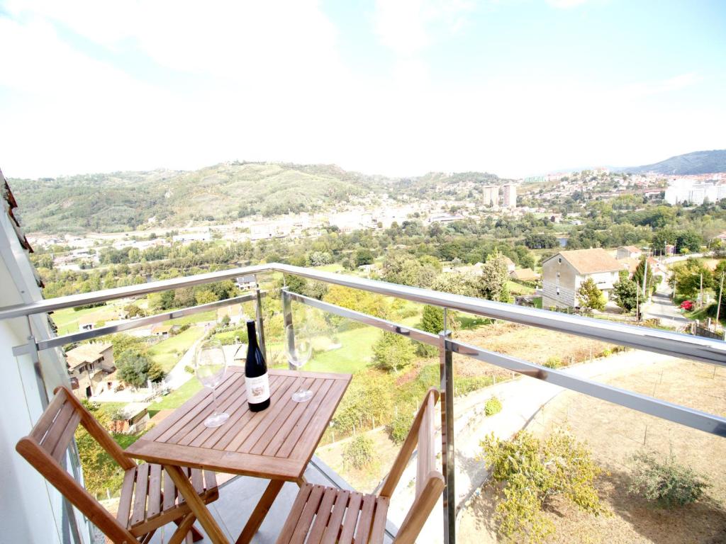 Una botella de vino sentada en una mesa de madera en un balcón en CASA MIRADOR REZA Alojamiento Termas en Ourense