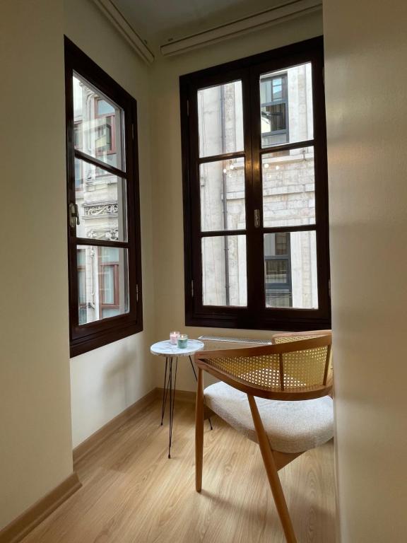 Zimmer mit 2 Fenstern, einem Stuhl und einem Tisch in der Unterkunft K&Y Apartments in Taksim İstiklal Street in Istanbul