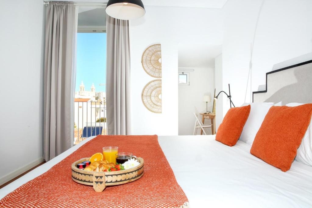 a bedroom with a bed with a tray of fruit on it at Xtraordinary Moments Apartment in Faro