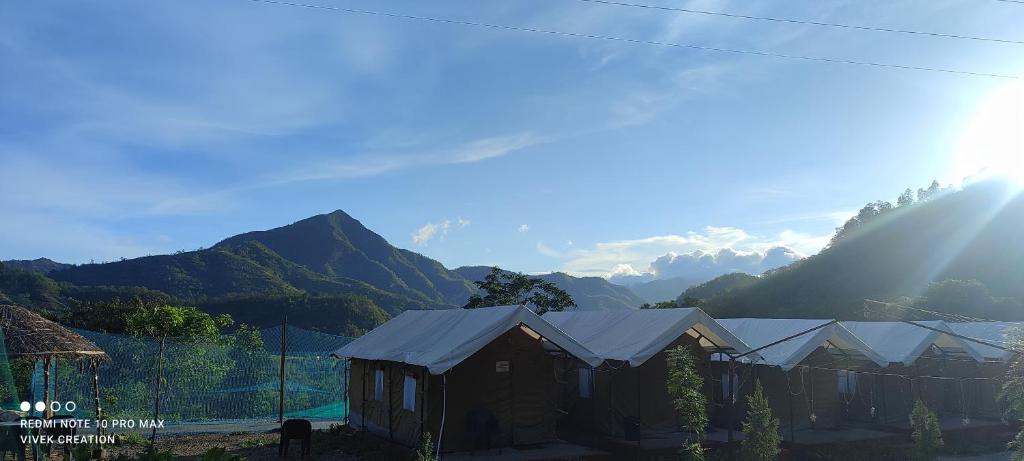 a group of houses with mountains in the background at The Jungle Mist Resort in Rishīkesh