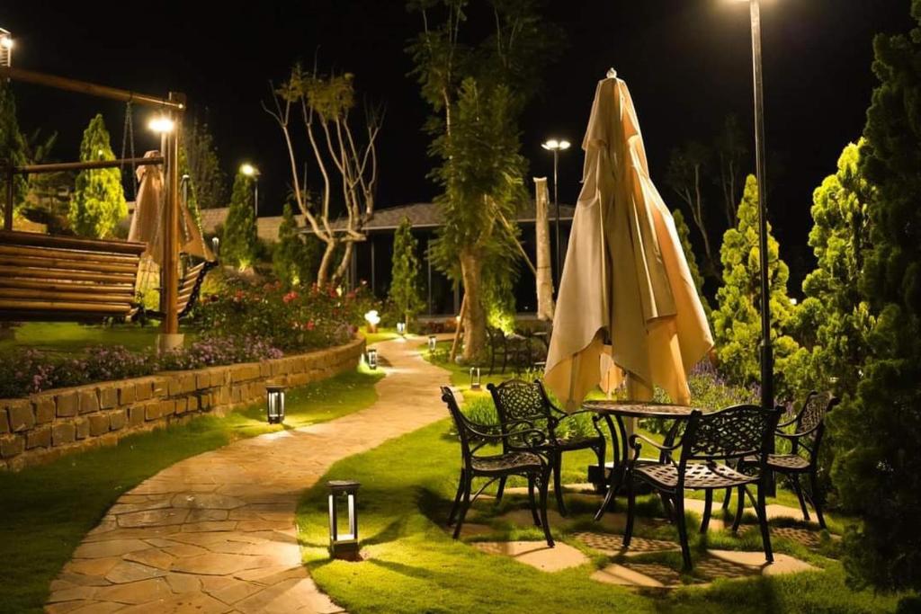 - une table et des chaises avec un parasol dans le jardin la nuit dans l'établissement Mya Lakeview Villa Biệt Thự, à Bảo Lộc