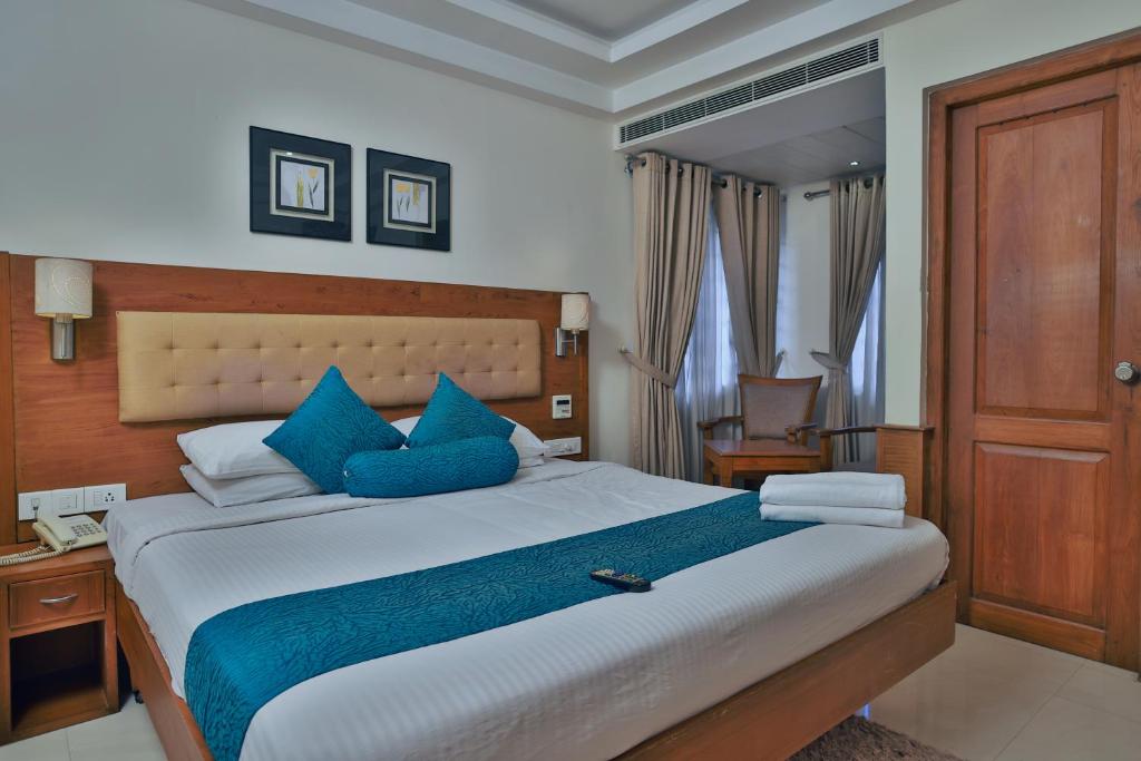 a bedroom with a large bed with blue pillows at Vishnu Inn in Guruvāyūr
