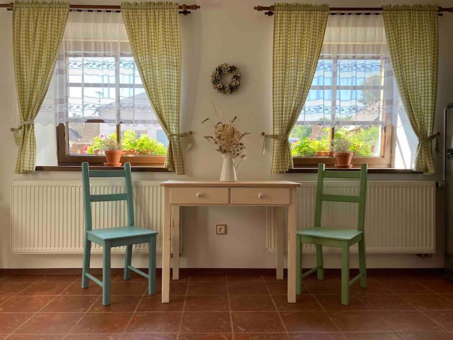two chairs and a table in a room with windows at The Dachshund's Chateau in Budíkov