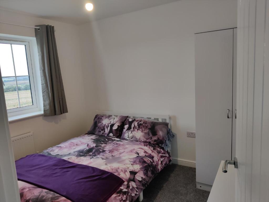 um quarto com uma cama roxa e uma janela em Cosyhome em Wellingborough