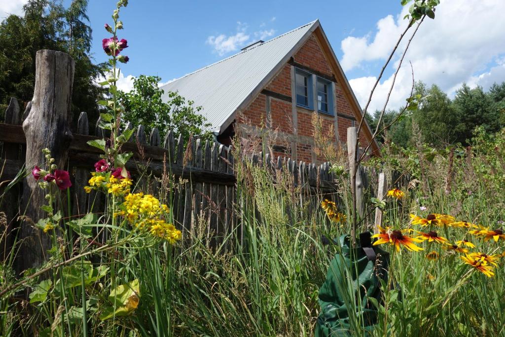 an old house in the middle of a field of flowers at Przytulny dom z kominkiem in Woldenberg Neumark