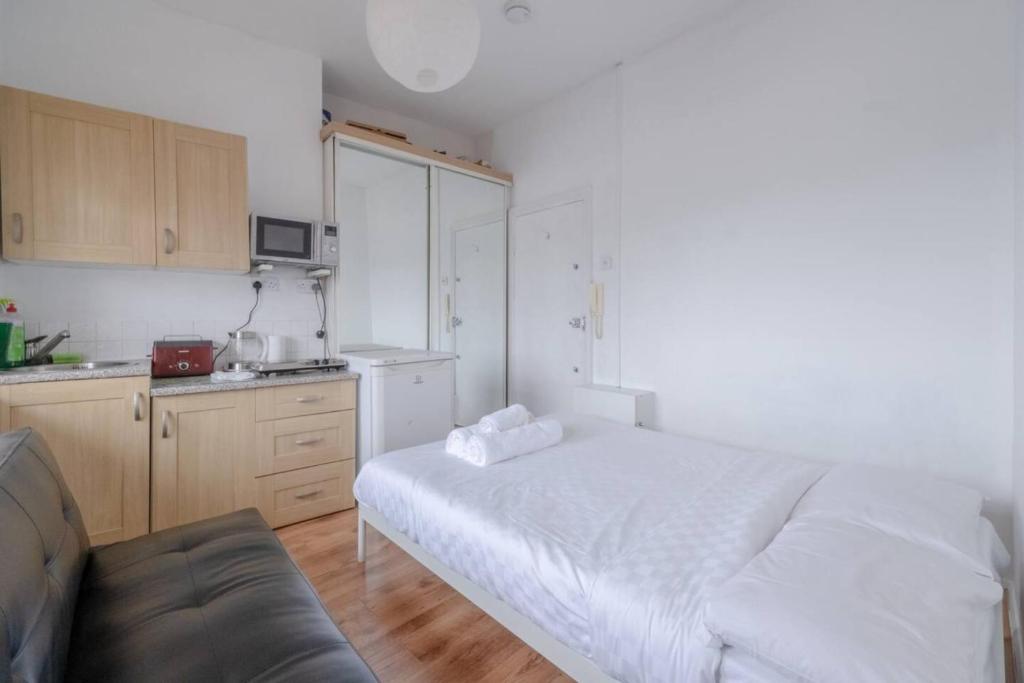 a bedroom with a white bed and a kitchen at Bright & Quaint Studio Flat - Hornsey! in London