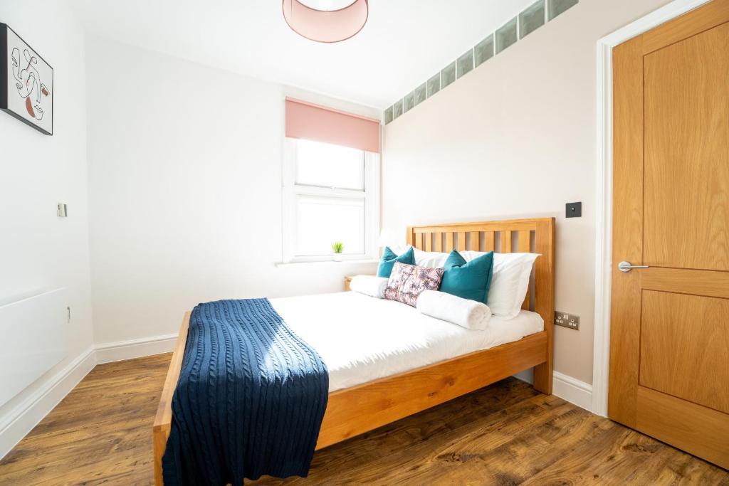 Schlafzimmer mit einem Bett mit blauen und weißen Kissen in der Unterkunft Redhill Garland- 1 bed ground floor apartment by LGW Short Lets in Redhill