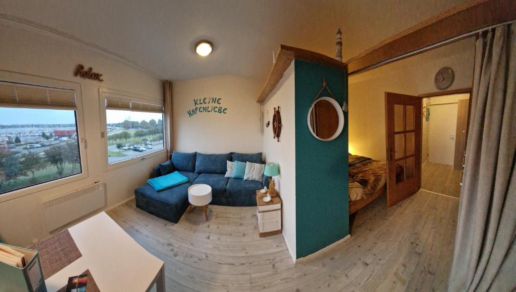 uma sala de estar com um sofá azul e uma grande janela em Kleine Hafenliebe em Fehmarn