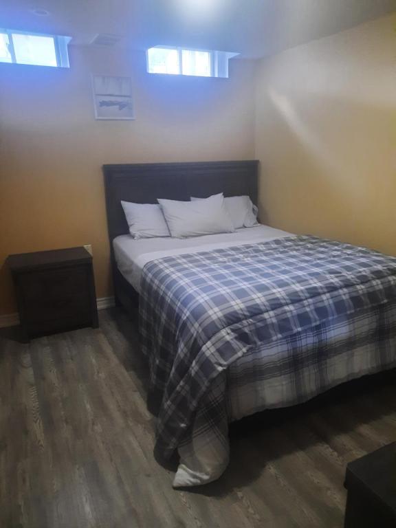 1 dormitorio con 1 cama con manta de cuadros azul en One bedroom basement suite with private living room and laundry., en Brampton