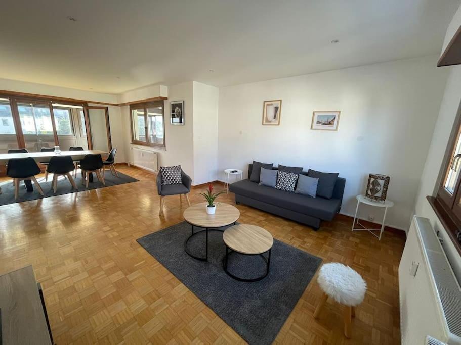 Una sala de estar con un sofá azul y una mesa. en Appartement de 115m2 à 10 min de Strasbourg & 25 min d'Europa Park !, en Illkirch-Graffenstaden