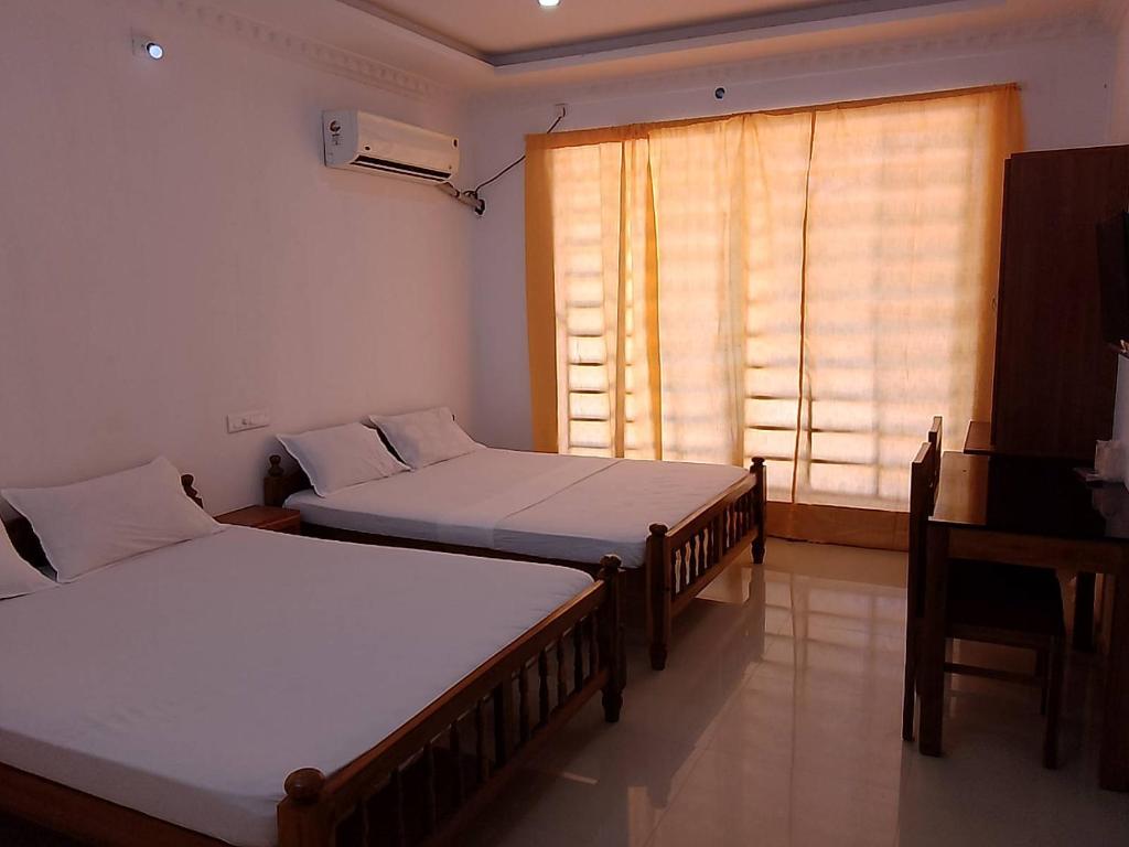 two beds in a room with a window at Somatheertham Panchakarma Resort in Kovalam