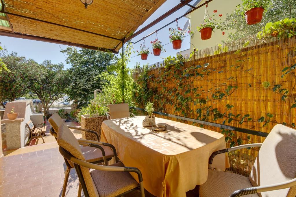 a patio with a table and chairs and a fence with plants at Apartment Oleander in Mali Lošinj