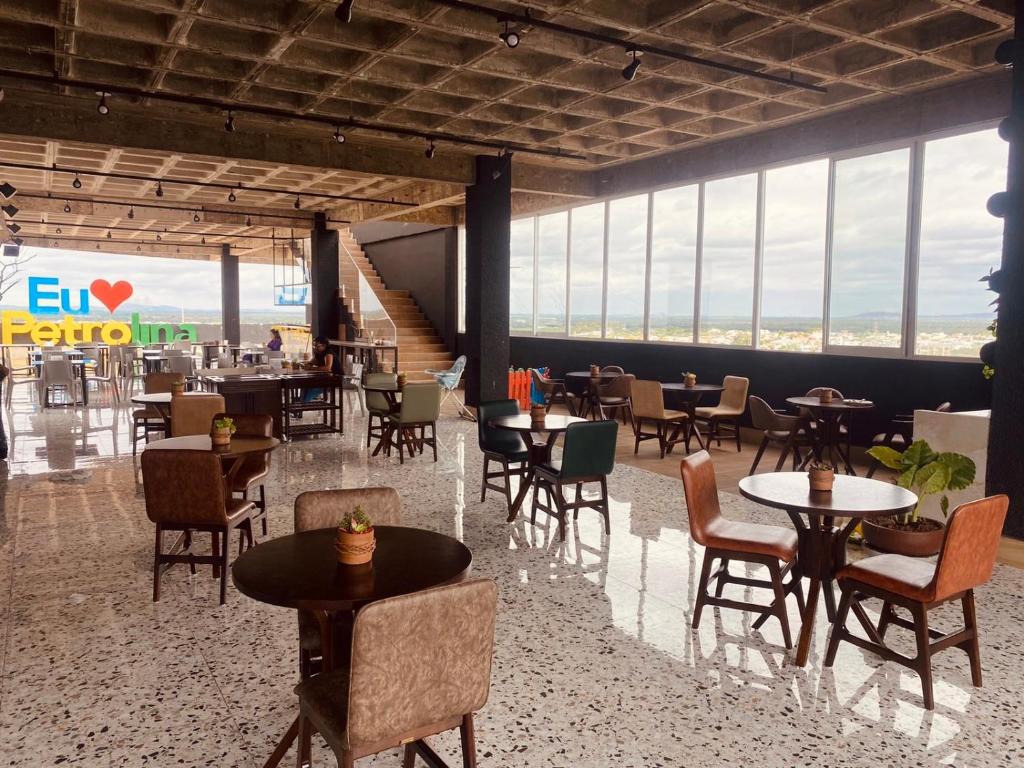 HOTEL NOVO CENTRO في بترولينا: مطعم بطاولات وكراسي ونوافذ كبيرة